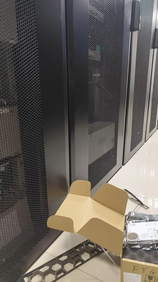 Replacement enterprise hard drive prepared beside the Dell server rack